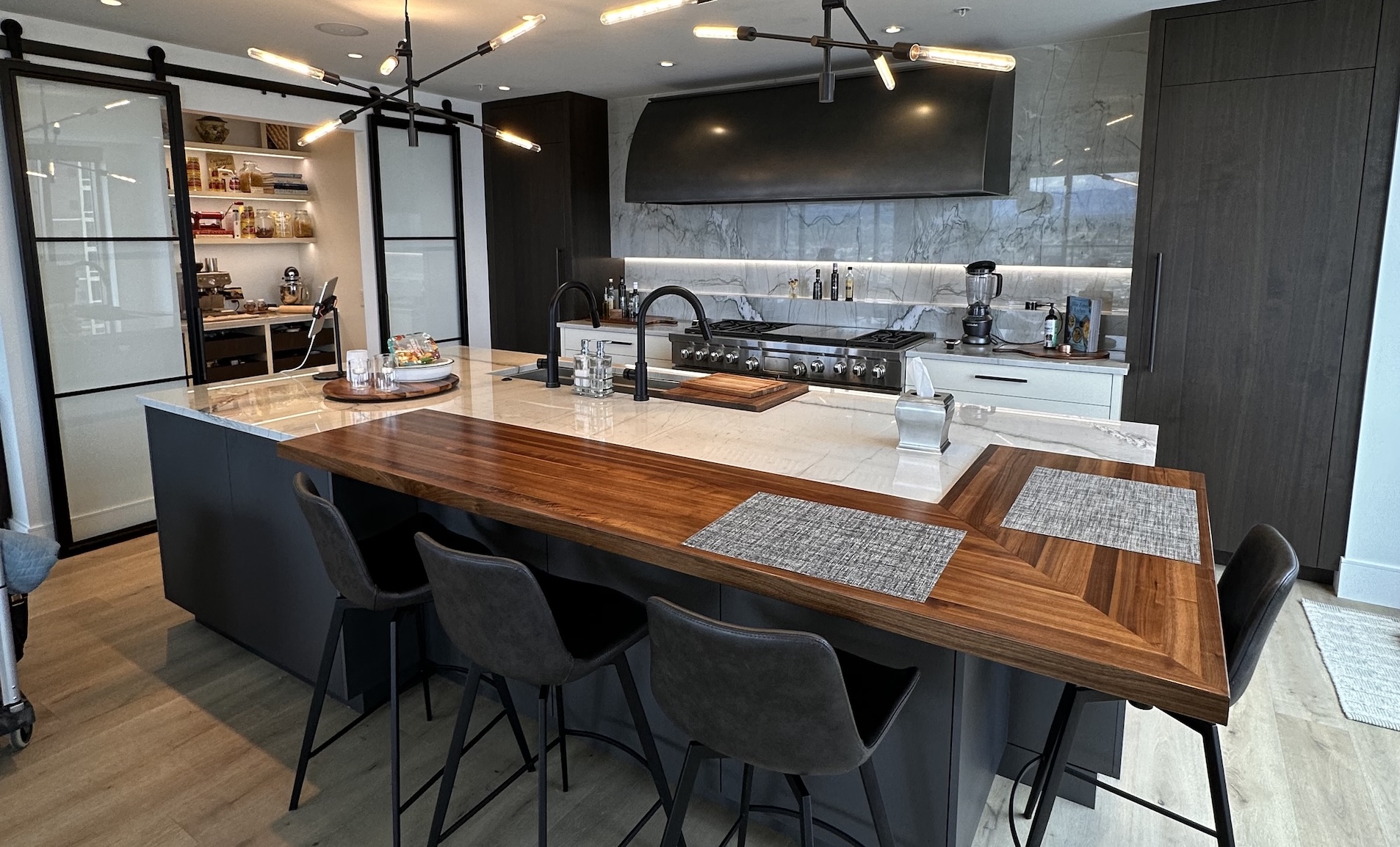 kitchen remodel at the four seasons in denver with custom pantry cabinets by Vonmod, steel and glass barn doors by White Shanty, white oak floors by Arrigoni, bar top by Grothouse, and range hood by Raw Urth